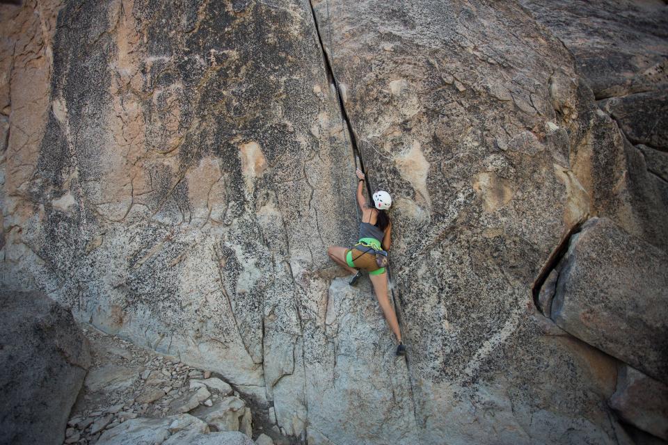Climber reaching overhead on a granite rock face