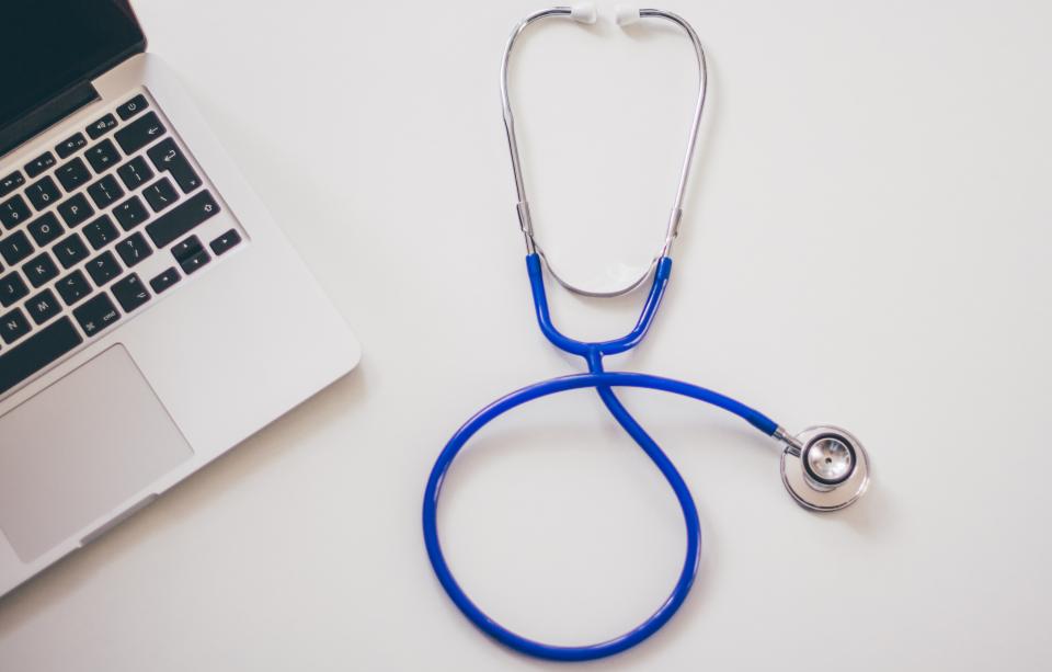 Stethoscope beside a laptop on a white desk