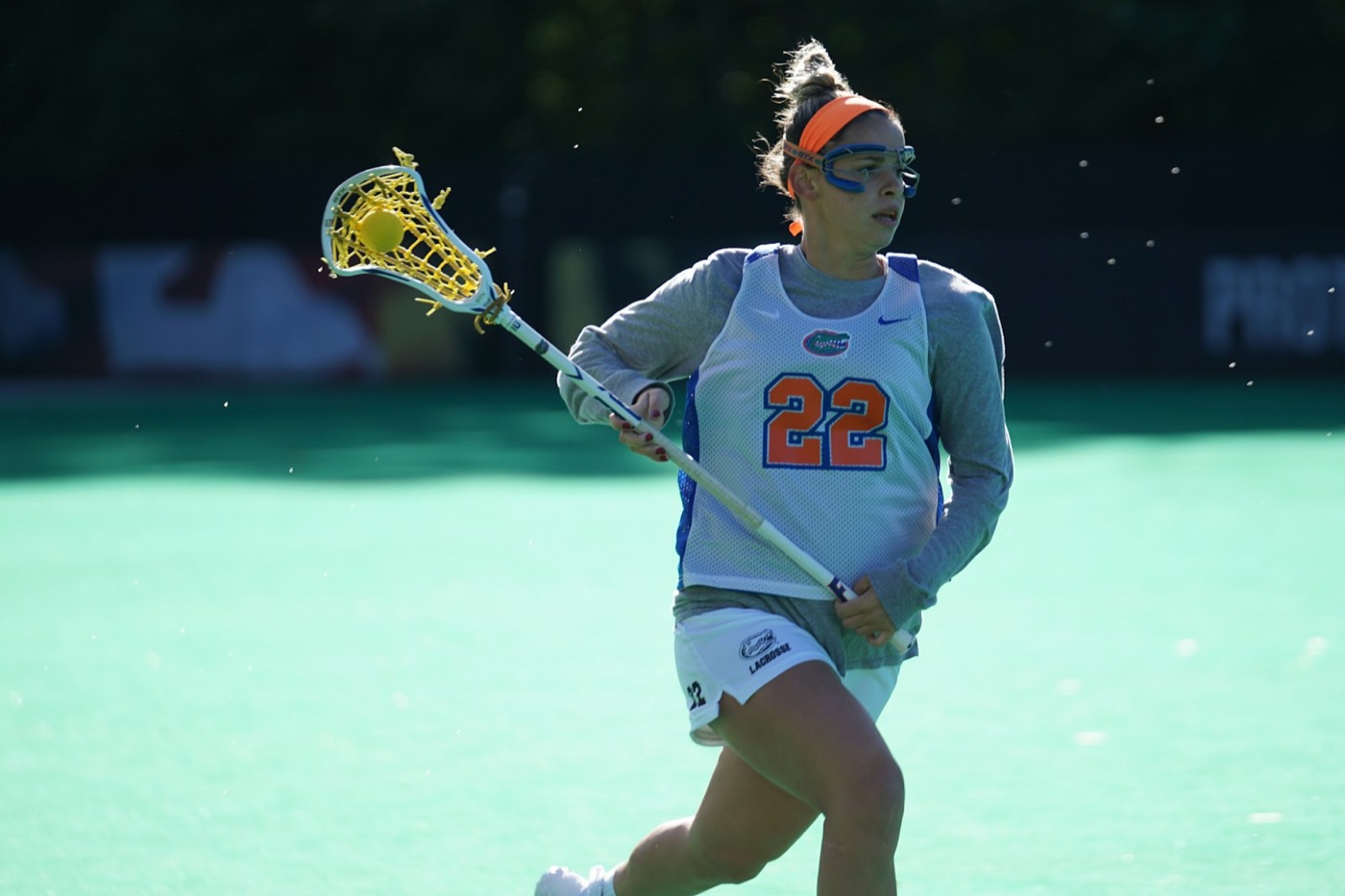 Women's lacrosse player running with her stick