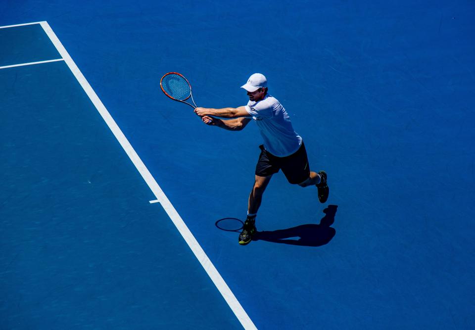 Tennis player reaching for a forehand on a blue hard court