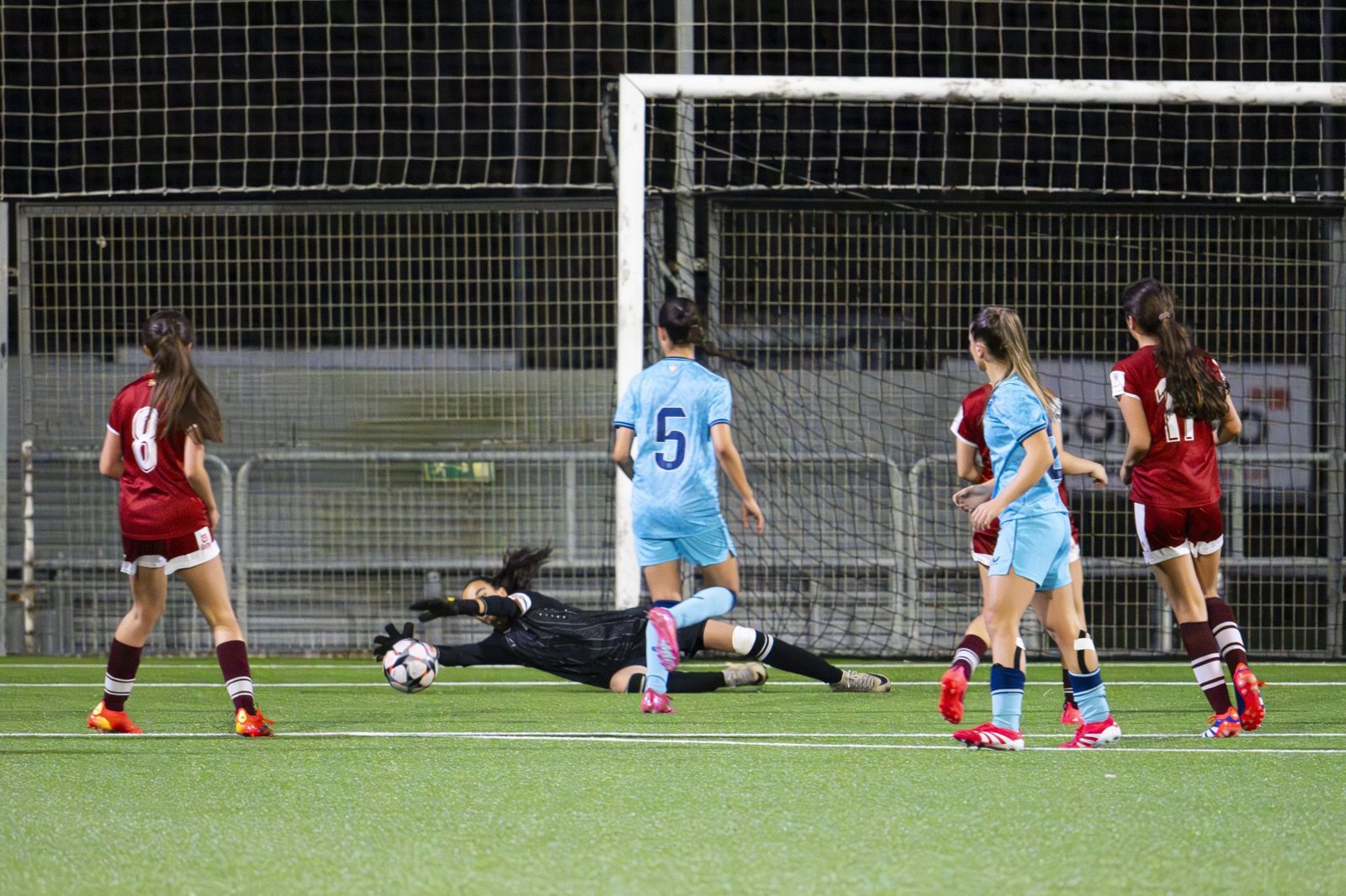 Girls' soccer game with the goalkeeper diving for a save