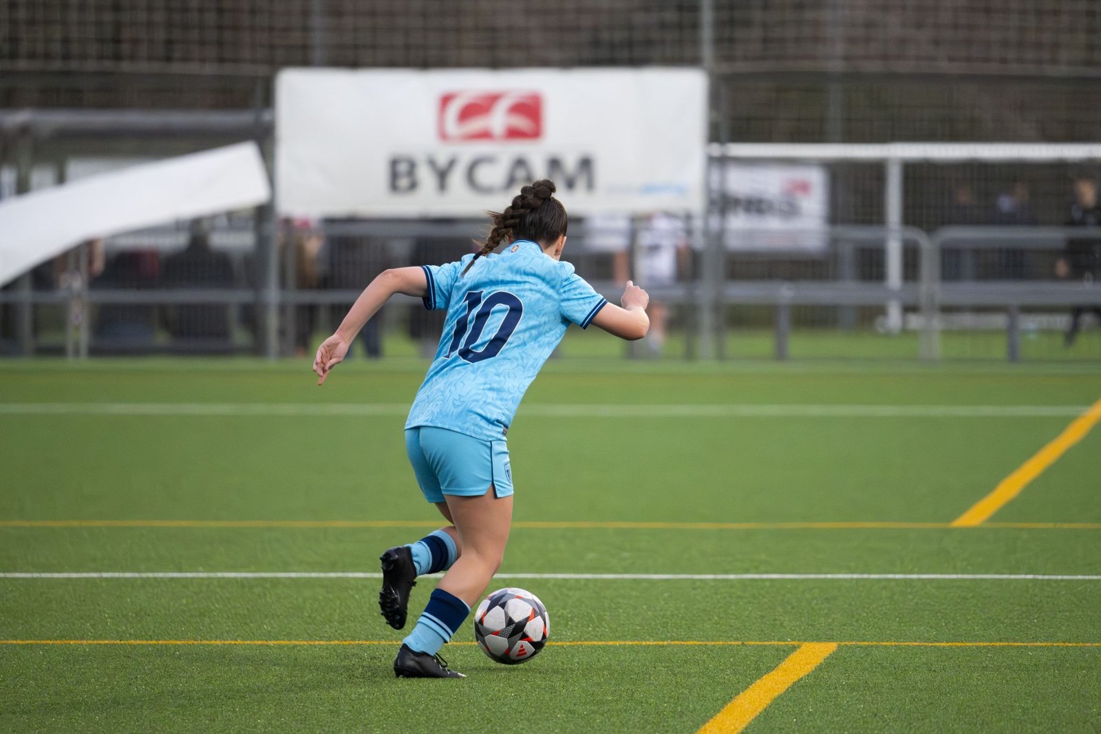 Young soccer player dribbling the ball on a turf field