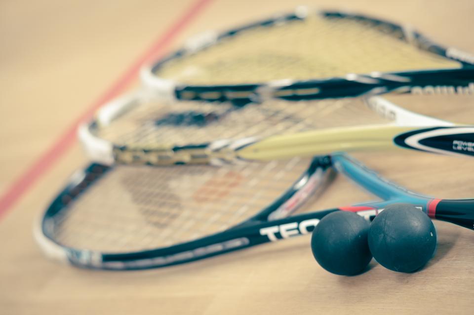 Close-up of two squash rackets and balls on a court